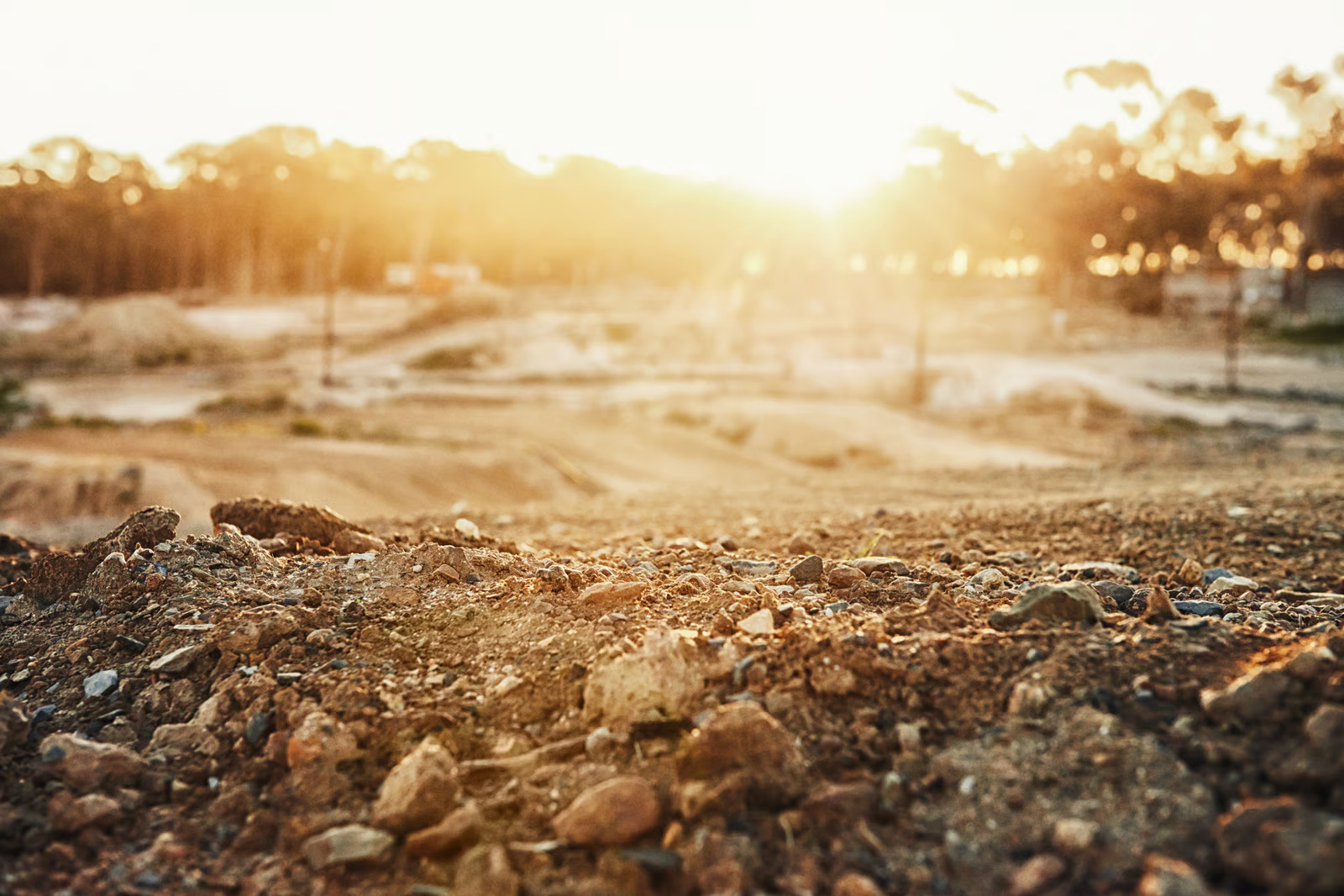 Graded construction site with exposed soil and earthwork illuminated by sunlight during a land development project.